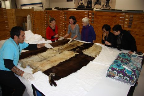 Te Papa staff look at the huru kurī cloak in Te Whare Pora, the collection store. Photograph by Moana Parata, copyright Te Papa.