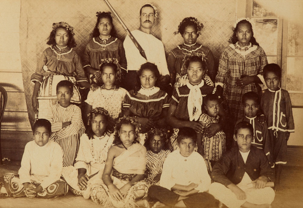 A group of Tokelau children and a white man stare at the camera with blank expressions