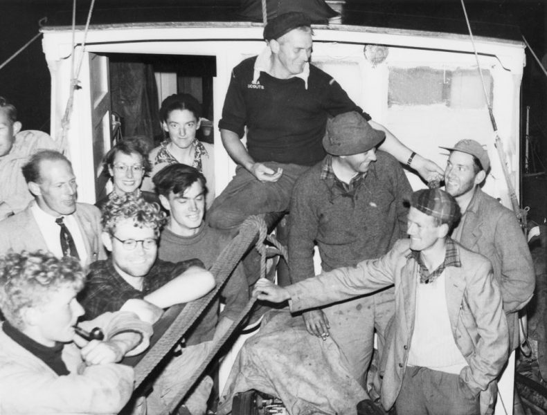 Members of the Chatham Islands 1954 Expedition on the aft deck of MV Alert on their return to Lyttelton, 12 February 1954. John Yaldwyn wearing his spare pair of glasses at lower left. Others approximately left to right are Jock Moreland, John McIntyre (with pipe), Ray Forster, Daphne Marshall, Betty Batham, Dave Garner, Alex Black (seated, captain), Dick Dell, George Knox and Elliot Dawson. Image: Te Papa MA_B.023472