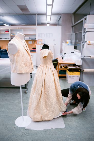 Textile conservator Anne Peranteau prepares William and Sarah Rhodes wedding waistcoat and dress for display. 27 Sept 2016. Te Papa