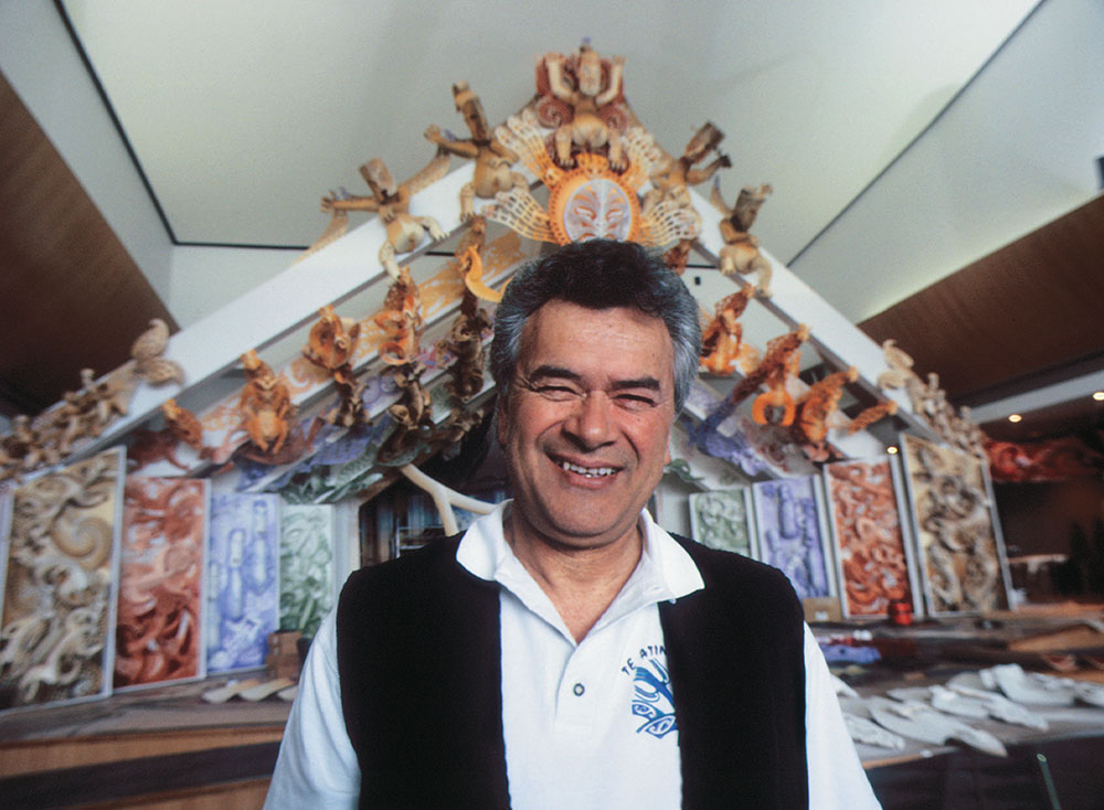 Man stands in foreground with marae in the background