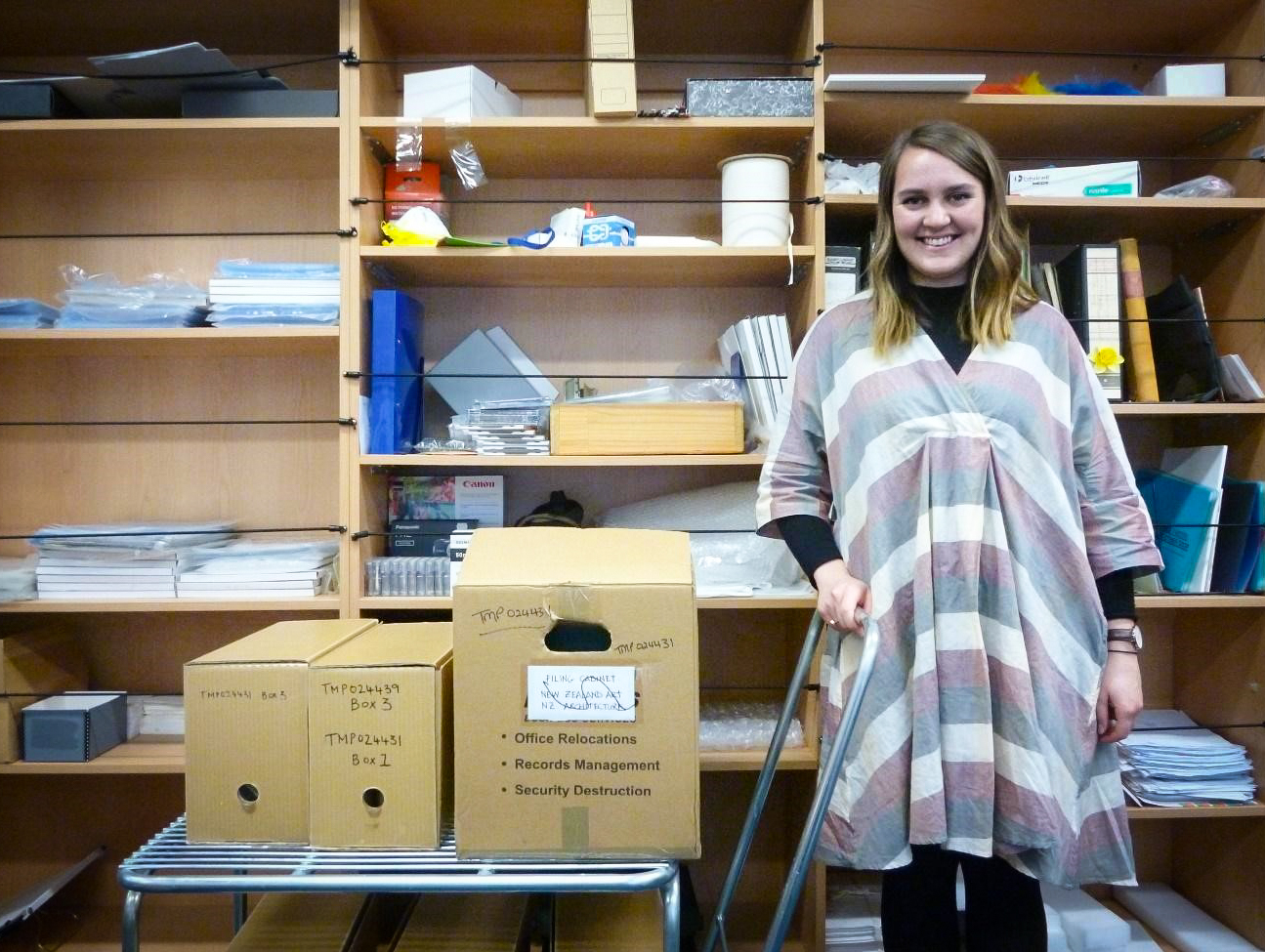 Ruby stands with some boxes in Te Papa's archives