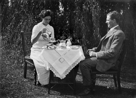 Man and woman sit at a table outside having tea