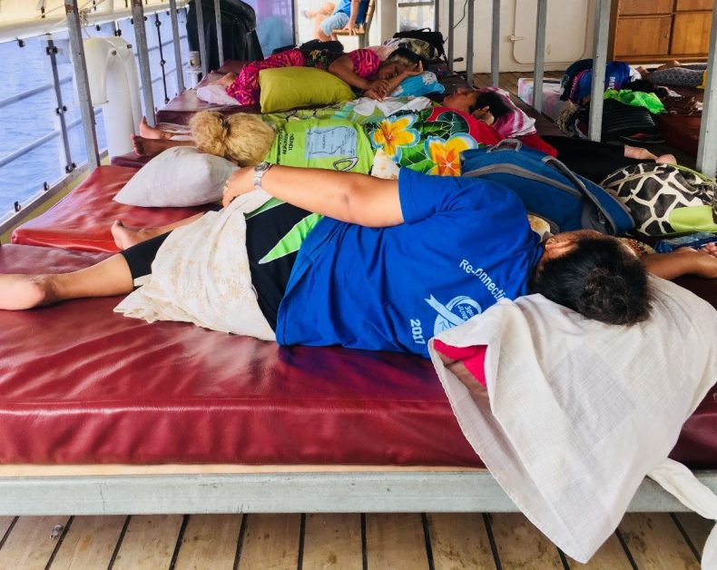 People sleeping on mattresses on the deck of a boat