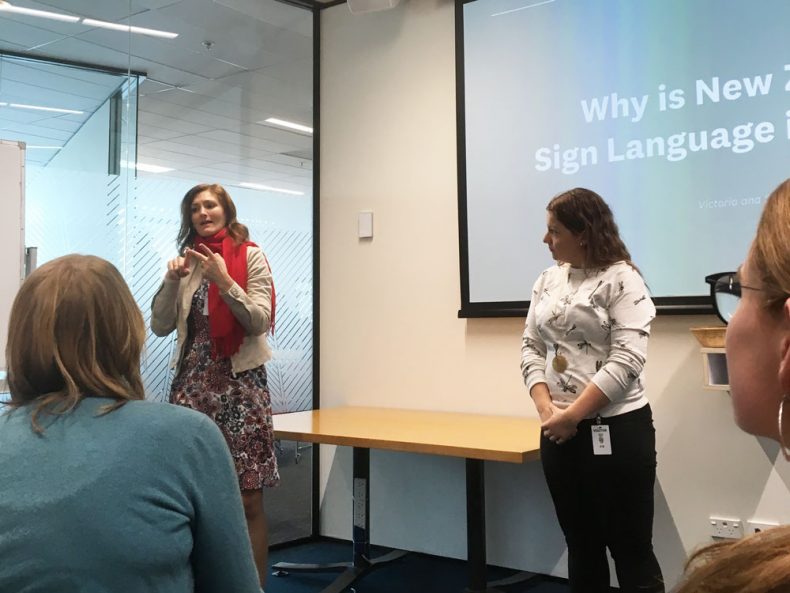 Two ladies using sign language in front of a group
