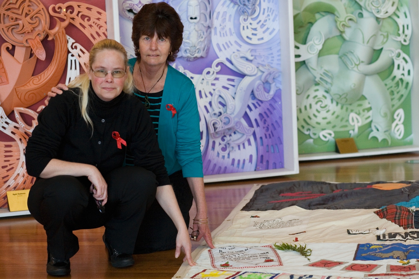 Two women pose with a panel of the New Zealand AIDS Memorial Quilt