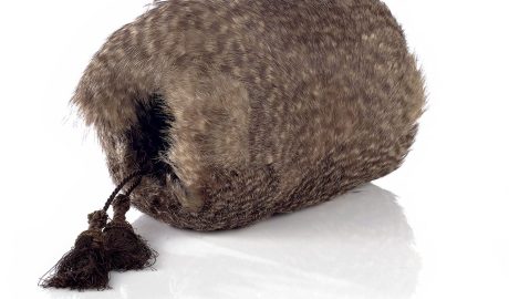 A kiwi feather muff for hands sitting on a white surface
