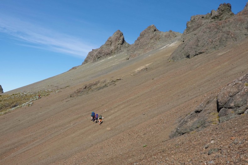 Members of our field team trekking across a steep and colourful scree in the Livingstone Mountains. Photo by Geoff Rogers January 2022.