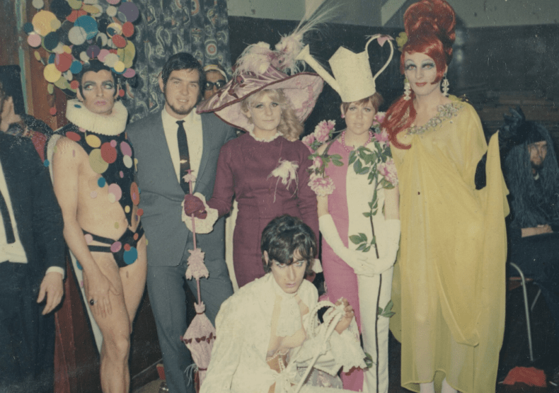 Seven people dressed in various costumes posing for the camera