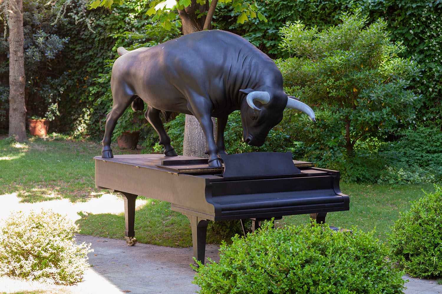Sculpture of a bull facing off on top of a grand piano